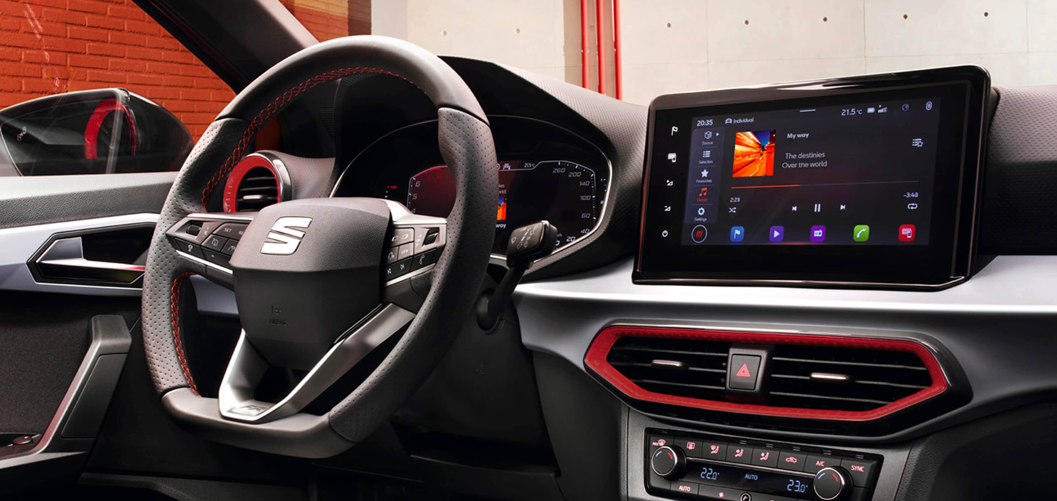 Interior view of a SEAT Ibiza highlighting the infotainment screen with music app in use.
